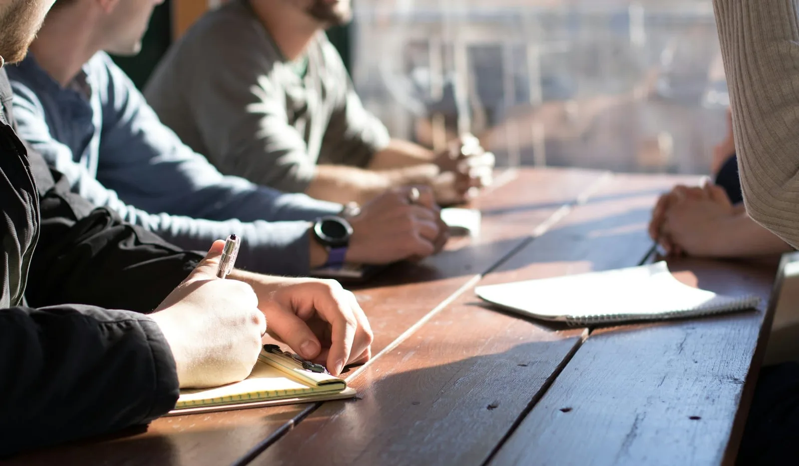 Colleagues taking notes around a table during an advisory meeting