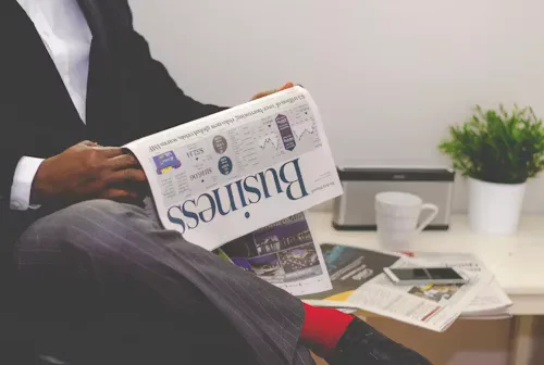 Business professional reviewing financial news and investment documents for market analysis.